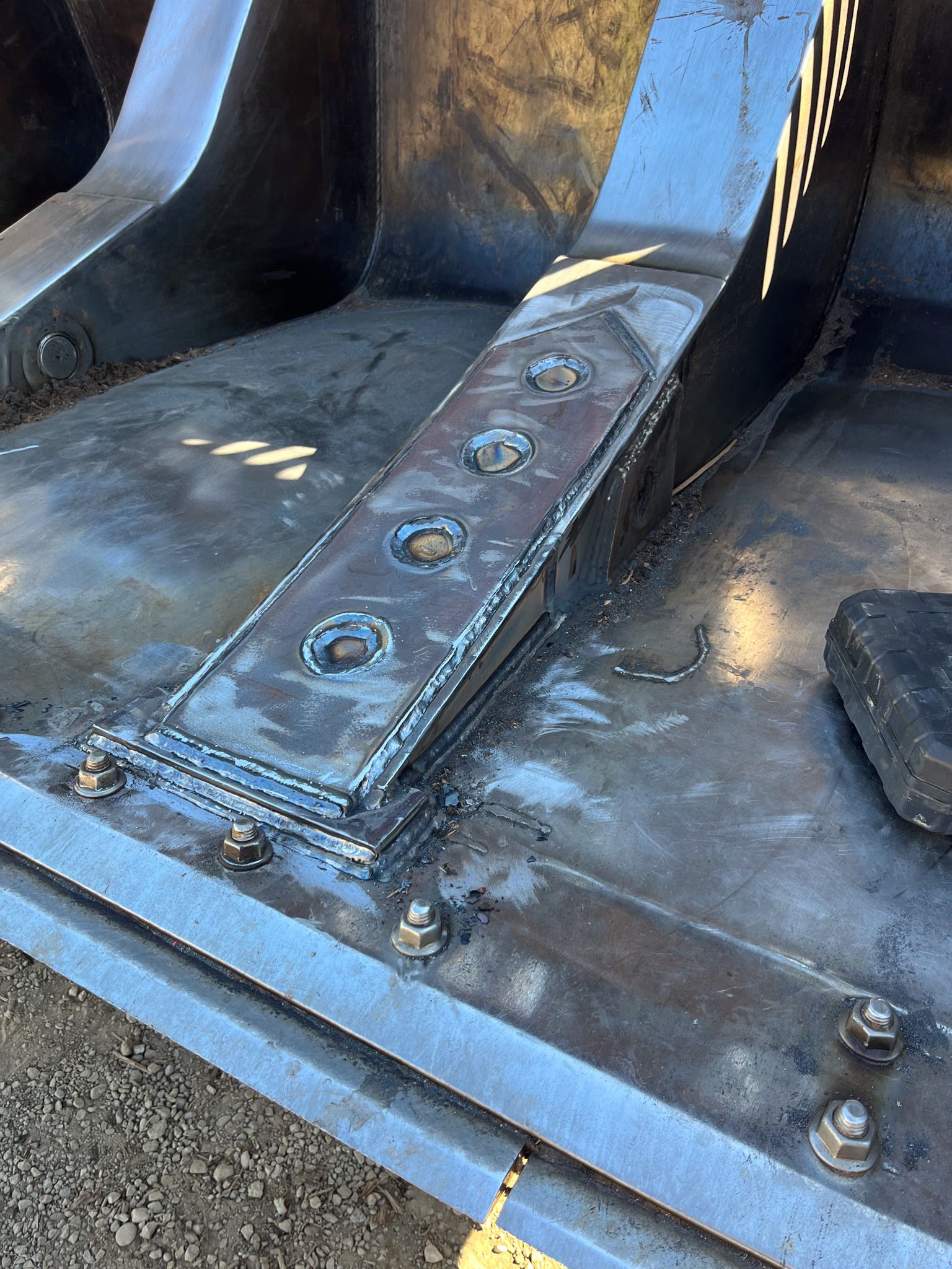 Fabricated steel bracket plug-welded and bolted onto a heavy steel plate deck