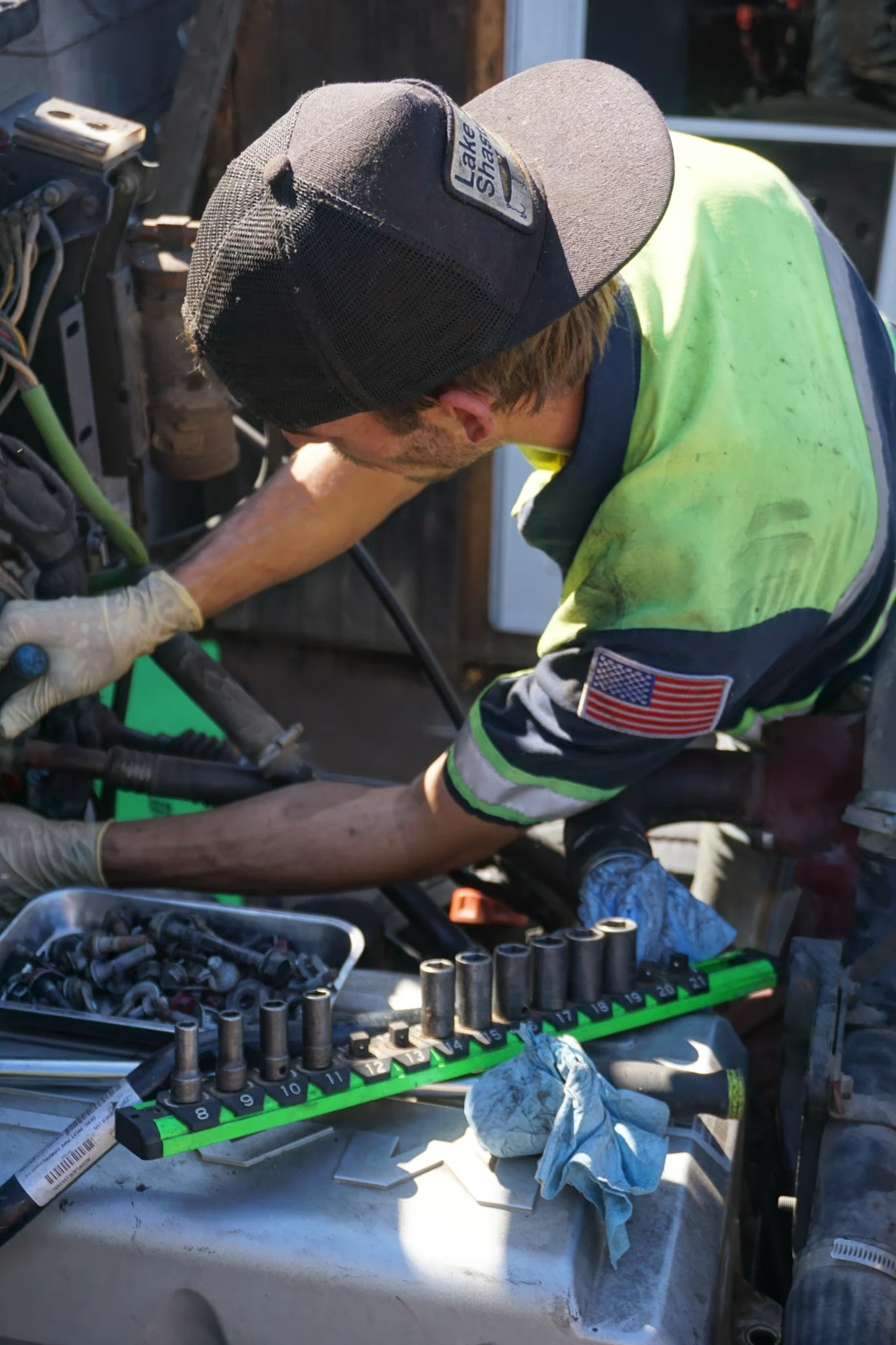 A technician works on hoses and fittings, an impact socket rail laid out on the machine